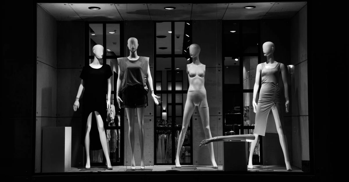 Des mannequins de mode élégants présentés dans une vitrine monochrome.