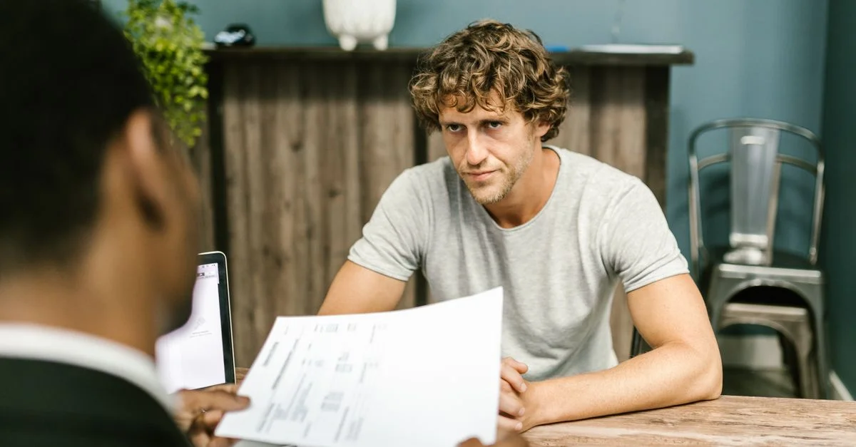 Deux hommes en discussion autour de documents lors d'une réunion d'affaires dans un environnement de bureau contemporain.