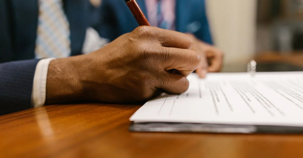 Gros plan d'un adulte signant un document légal avec un stylo dans un bureau.