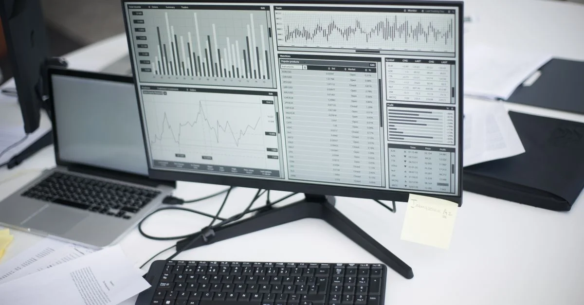 Un espace de travail professionnel avec des ordinateurs et des graphiques analytiques sur un moniteur, symbolisant un environnement d'affaires moderne.