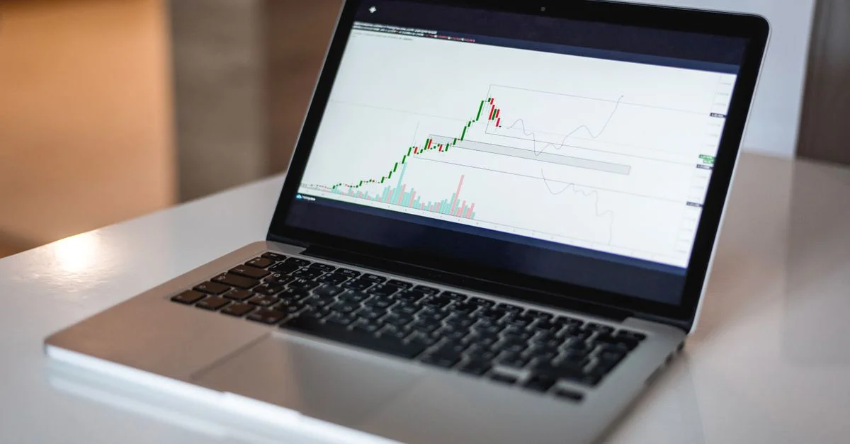 Gros plan d'un ordinateur portable montrant un graphique de trading financier, idéal pour des thèmes de finance et de technologie.