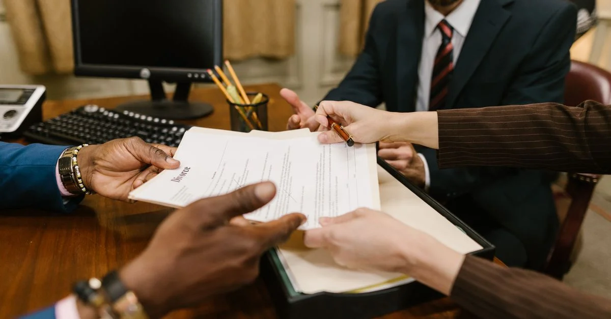 Réunion professionnelle avec des personnes signant des documents juridiques dans un cadre de bureau.