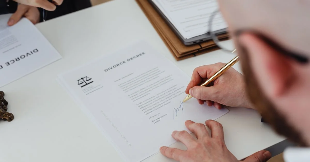 Gros plan d'une personne signant un décret de divorce sur un bureau.