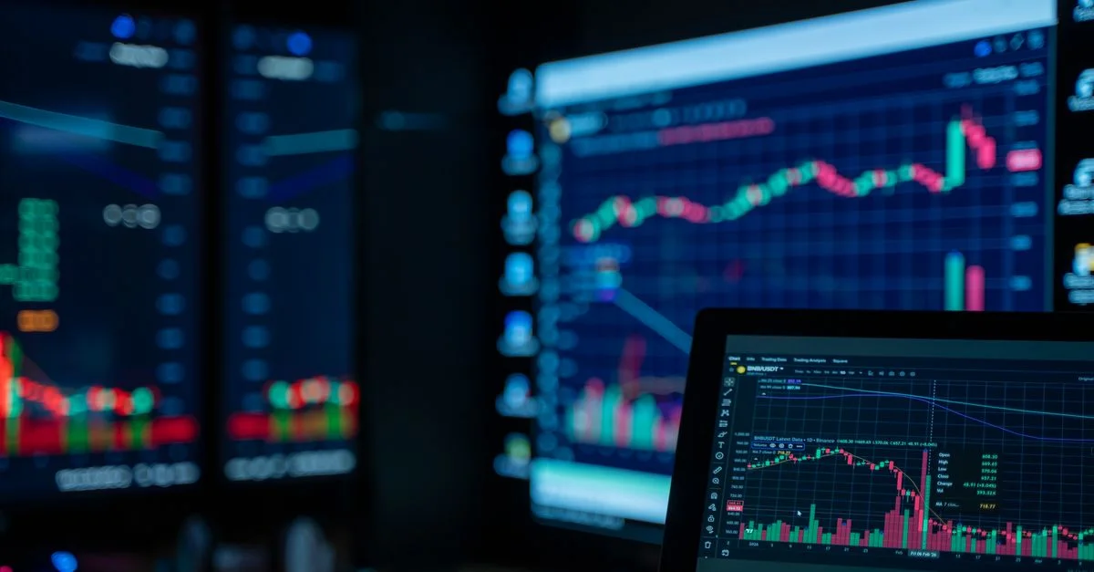 Des écrans affichant des graphiques boursiers dans une pièce faiblement éclairée, idéal pour les thèmes liés à la finance et au trading.